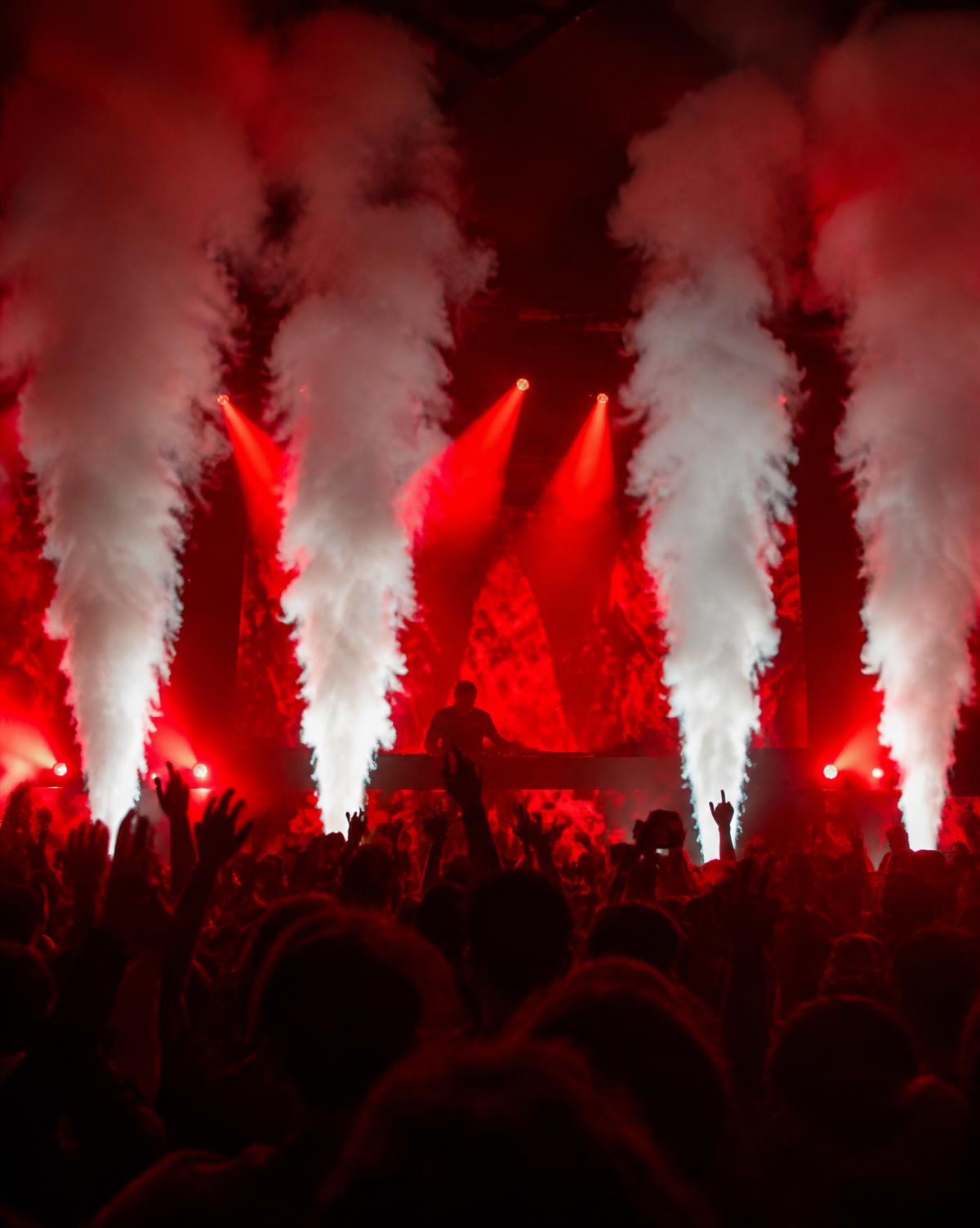 CO₂ cannons firing jets of vapor above a DJ stage